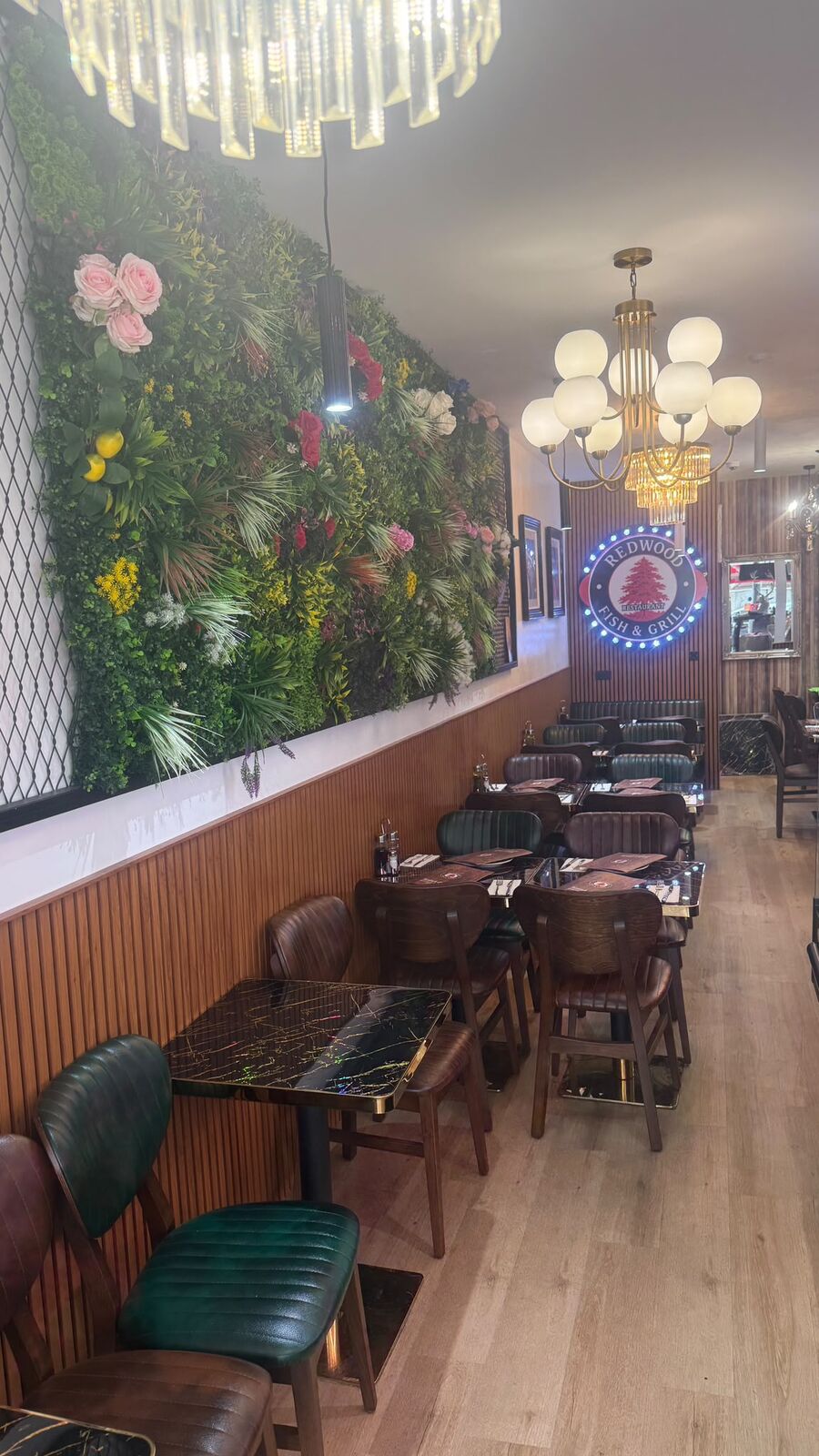 Dining room at Redwood Fish & Chips with a living green wall, chandeliers and marble tables